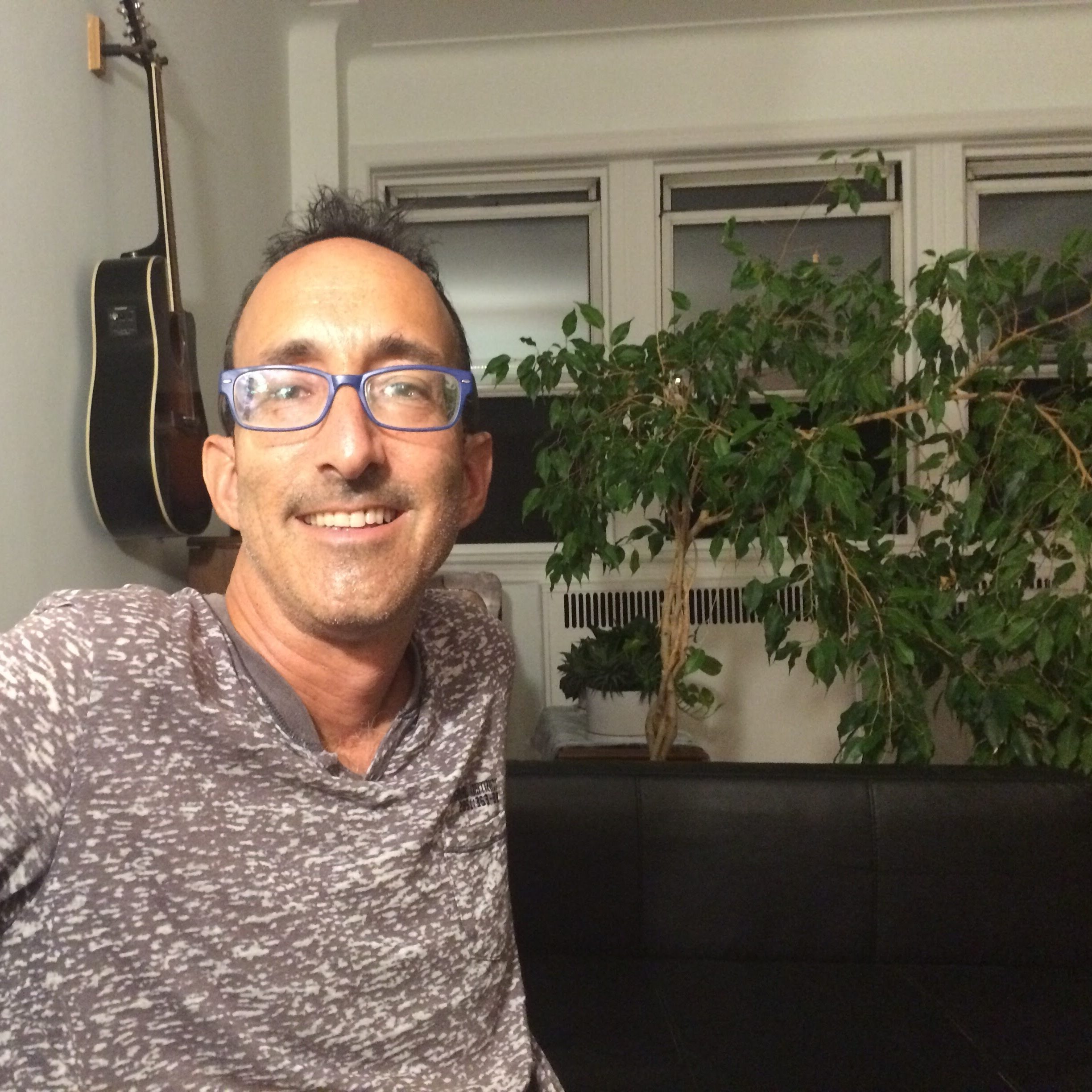 Author and drummer, David Rothman. David is a white man with short dark hair and glasses and a narrow, smiling face. He wears a gray t-shirt and glasses. 